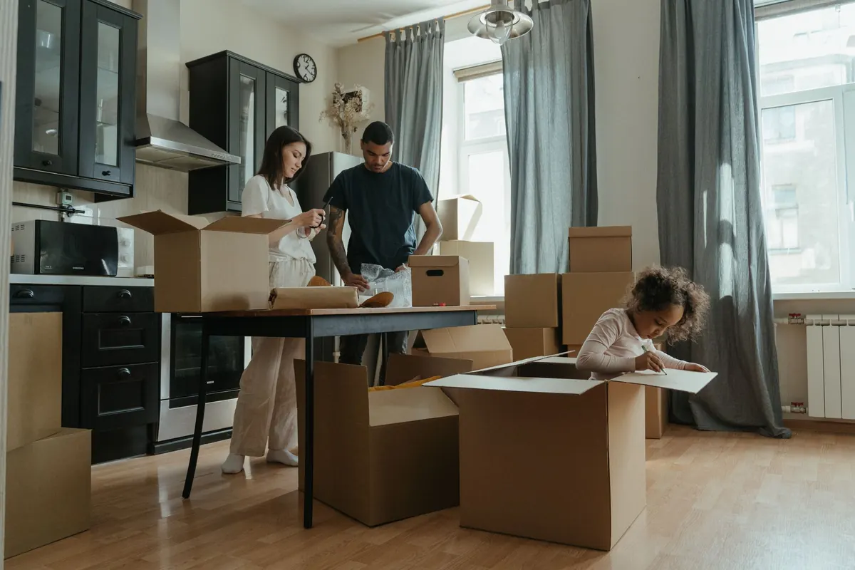Família desembalando caixas na cozinha do apartamento novo
